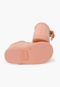 Botas de tobillo color durazno con parte superior de lienzo texturizado y suela de goma, que presentan un detalle de hebilla lateral y costuras visibles.