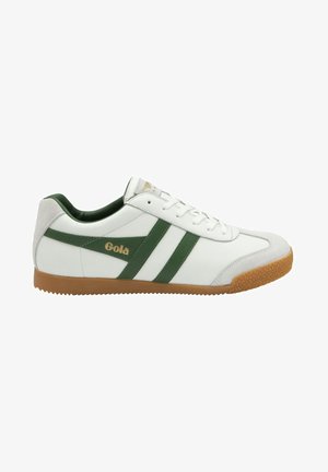 White sneaker with green leather stripes and gold logo. Textured tan rubber sole and grey suede accent at the heel. Lace-up design.