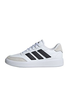 Zapatilla deportiva blanca con rayas negras, detalles de ante, puntera redonda, suela de goma y cordones planos. Cuenta con un collar y lengüeta acolchados.