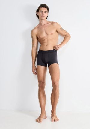 Schwarze Boxerbriefs aus elastischem Stoff mit einem weichen Bund. Das Design ist enganliegend und weist keine sichtbaren Muster oder Logos auf.