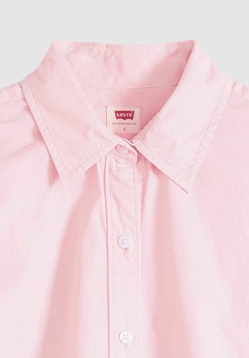 Chemise rose clair à boutons avec col pointu et boutons blancs, affichant l'étiquette de la marque Levi's à l'intérieur du col en taille petite.
