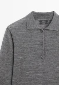 Szary wełniany sweter z kołnierzykiem, rozpięciem na trzy guziki i gładką fakturą. Metka wskazuje, że materiał to 100% wełna.