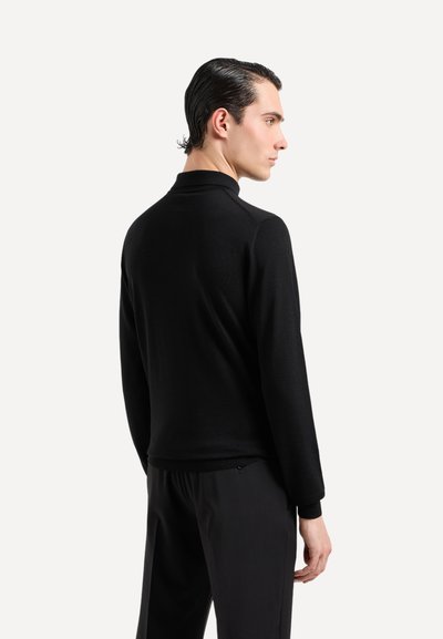 Pullover nero con colletto alto, maniche lunghe e texture a costine. Realizzato in un tessuto morbido, progettato per una silhouette aderente.