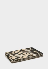 Sciarpa di lana piegata con motivo a strisce zebrate nere e beige su uno sfondo bianco semplice.