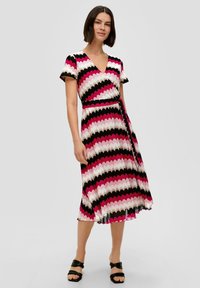 Kurzes, ärmelloses Wickelkleid mit einem Zickzackmuster in Pink, Schwarz und Weiß. Hergestellt aus leichtem Stoff mit einem Gürtel in der Taille.