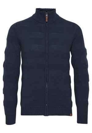 Tumesinine kootud sviiter, millel on kõrge kaelus, esine lukuga, soonikud käeotus ja kangas struktuurse horisontaalse mustriga.