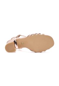 Sandal in nudo con cinturini, parte superiore trasparente, suola piatta e tacco a blocco piccolo. Presenta hardware minimale e texture liscia.
