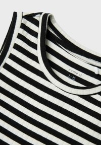 Débardeur à rayures noires et blanches avec une texture côtelée, doté d'un col rond et d'une étiquette à l'intérieur affichant le nom de la marque et la taille.