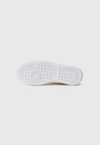 Hvit sneakersåle med et teksturert rutenettmønster og sirkulært logodesign, glatte kanter og en subtil fargegradient mot sidene.