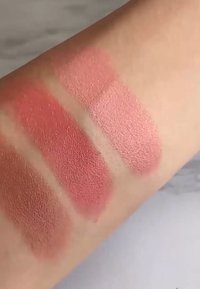 Tres muestras de colorete en un tono de piel clara. Los tonos varían desde un durazno suave hasta un rosa apagado, con acabado mate, textura suave y sin brillo visible.