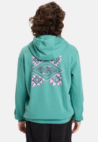 Turquoise hoodie with pink geometric pattern on the back, featuring a drawstring hood and a relaxed fit design. Soft texture.