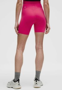 Svijetlož Pink sportske kratke hlače s visokim strukom, izrađene od rastezljivog materijala. Imaju logo detalj i dizajn do sredine bedara.