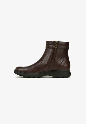 Bottines en cuir marron avec une fermeture éclair sur le côté, semelle en caoutchouc et deux sangles décoratives autour de la cheville pour un détail supplémentaire.