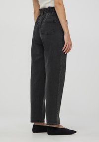 Czarne dżinsowe spodnie z wysokim stanem, elastycznym pasem, szerokimi nogawkami i dwiema tylnymi kieszeniami, teksturowany materiał i wykończenia z mankietami.