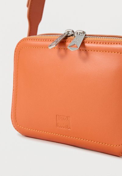 Πορτοκαλί δερμάτινη τσάντα ώμου με διπλούς ασημένιους φερμουάρ και εγχάρακτο λογότυπο στο μπροστινό μέρος, με ραμμένες άκρες και ιμάντα.