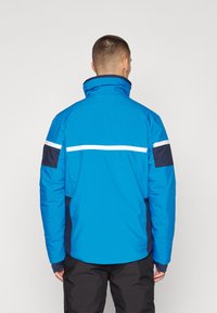 Blaue gepolsterte Jacke mit hohem Kragen, weißen horizontalen Streifen auf dem Rücken und marineblauen Akzenten auf den Schultern.