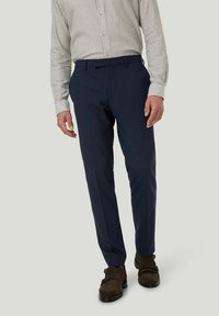 Marineblaue maßgeschneiderte Hose aus strukturiertem Stoff, mit geradem Bein, frontalen Taschen und einem Bund mit Gürtelschlaufen, kombiniert mit braunen Schuhen.