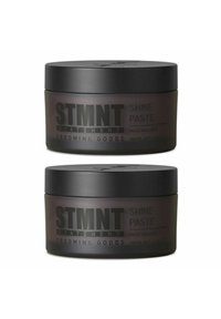 Two jars of STMTNT Shine Paste, matte black lids, transparent dark containers, labeled in bold white lettering, 100 mL.