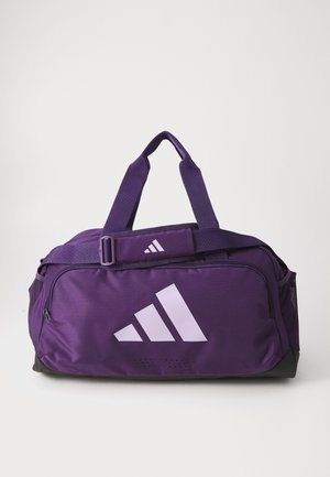 Violets sporta soma ar lielu baltu Adidas logo, divām rokturiem, regulējamu siksnu un sieta sānu kabatām. Audums ir gluds un izturīgs.