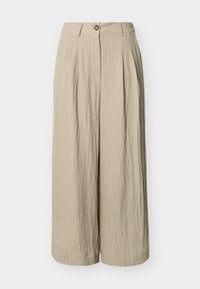 Pantalon beige à jambes larges, taille haute, fermeture par bouton, passants pour ceinture et plis verticaux subtils sur le tissu.