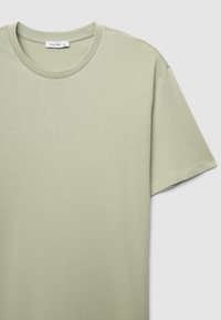 T-shirt in cotone verde chiaro con scollo rotondo e maniche corte. Texture liscia, design casual e dettagli di cuciture minime.