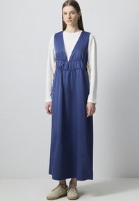 Rochie maxi bleu marin cu decolteu adânc în V, talie ajustabilă cu șnur și buzunare laterale. Prezintă o textură fină și o siluetă lungă.