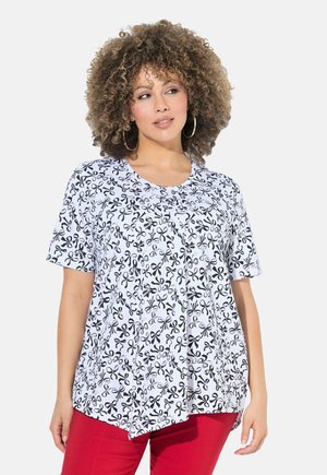 Haut à manches courtes en tissu léger avec un motif floral noir et blanc, encolure ronde et ourlet asymétrique.