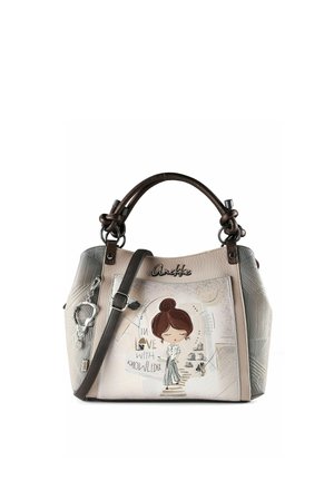 Beige Handtasche mit dunkelbraunen Griffen, einer Zeichnung einer Frau, dem Text "Verliebt in Wissen" und einem befestigten silbernen herzförmigen Anhänger.