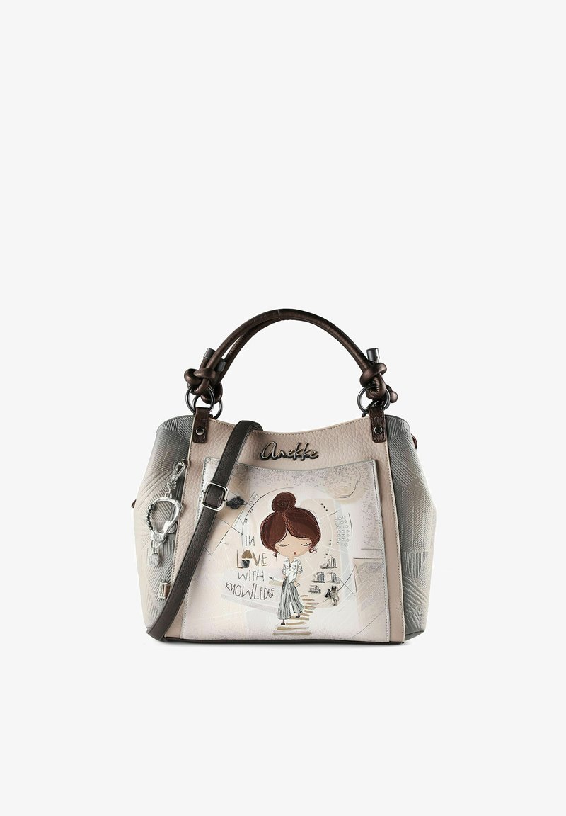 Bolso beige con asas marrón oscuro, ilustración de una mujer de dibujos animados, texto "Enamorado del conocimiento" y un colgante plateado en forma de corazón adjunto.