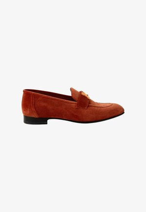 Mocassin homme en daim marron avec un petit talon et une boucle décorative sur fond blanc.