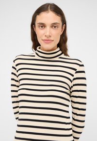 Schwarz-weiß gestreifter Rollkragenpullover aus geripptem Stoff mit figurbetontem Schnitt und langen Ärmeln.