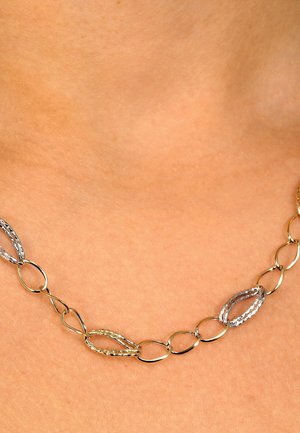 Halskette aus Gold- und Silberfarben mit abwechselnd strukturierten und glatten ovalen Formen, die auf einem neutralen Hautton liegt.