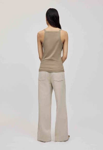 Beige ribbed tank top with adjustable spaghetti straps paired with light beige wide-leg pants featuring back pockets and visible stitching.
