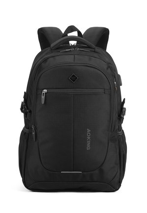Zaino nero con numerosi scomparti con zip, spallacci imbottiti, tasche laterali e una maniglia superiore, in posizione verticale su uno sfondo bianco.