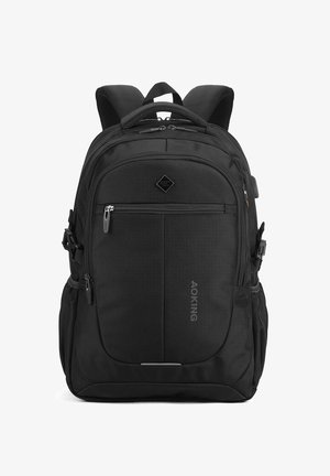 Sac à dos noir avec plusieurs compartiments zippés, des bretelles rembourrées, des poches latérales et une poignée supérieure, se tenant debout sur un fond blanc.