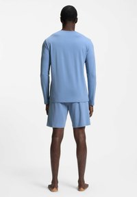 Long-sleeve, light blue shirt with a crew neckline paired with matching shorts, both made of a smooth, soft fabric.