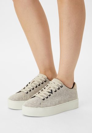 Kremowe sneakersy o fakturowanej powierzchni, z okrągłym noskiem, czarnymi oczkami i beżowymi sznurowadłami. Podniesiona biała podeszwa zapewnia dodatkową wysokość.