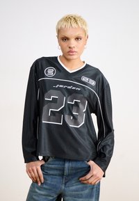 Svart langermet jersey med V-hals, prydet med hvite detaljer og et stort "23" på forsiden. Laget av glatt, lett materiale.