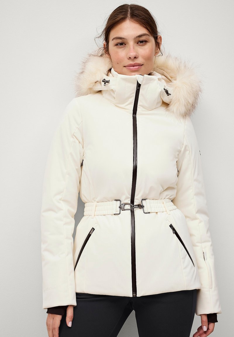 Ivory winterjas met nepberenhood, kort model met riem, zwarte rits en twee zijzakken. Gladde textuur, getailleerde pasvorm en warm materiaal.