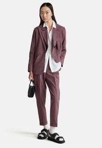 Completo a quadri prugna composto da un blazer sartoriale e pantaloni coordinati, abbinato a una camicia bianca, una borsa nera e sandali neri chunky.
