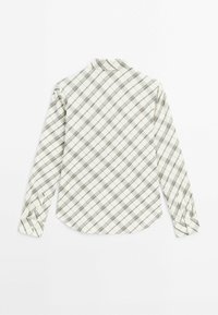 Chemise blanche à manches longues avec motif à carreaux diagonaux noirs, col écarté et poignets boutonnés, posée à plat montrant le dos.