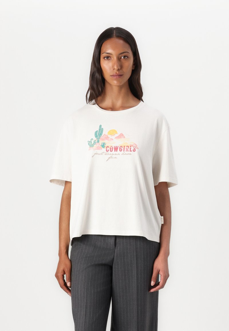 White short-sleeve t-shirt featuring a colorful graphic of cacti, mountains, and a sun with the text "COWGIRLS" in a playful font.