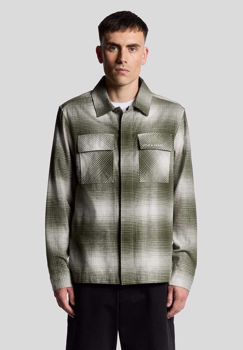 Chemise d'extérieur à carreaux verts et blancs avec un col, deux poches poitrine et une coupe droite. Fabriquée en tissu texturé avec une finition lisse.
