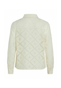 Chemise en dentelle, légère, couleur crème, motif losange, manches longues, col avec fermeture à boutons, tissu texturé.