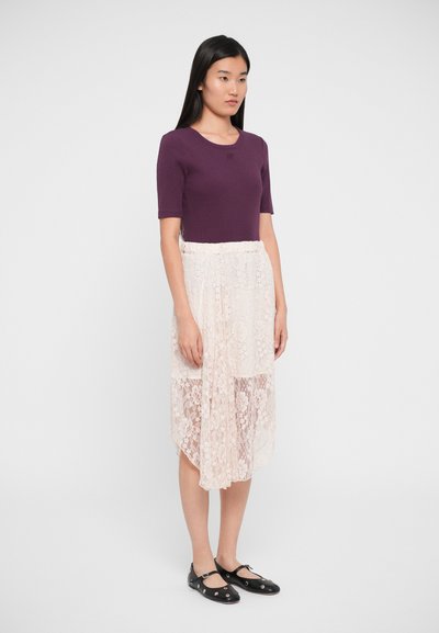 Top violet cu mânecă scurtă, asortat cu o fustă ușoară din dantelă, cu modele florale, straturi translucide și pantofi negri cu talpă plată cu accente.