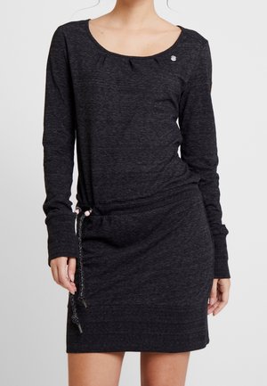 Vrouw draagt een donkergrijze jurk met lange mouwen, een ronde halslijn en een taille met trekkoord, getoond van schouders tot halverwege de dijen.