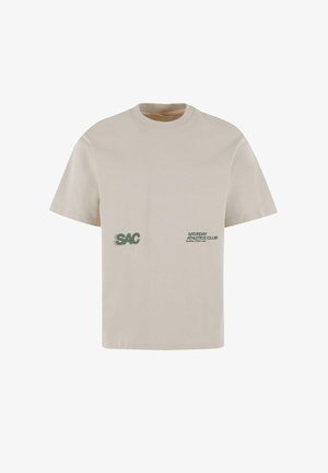 Svetlo bež majica s kratkimi rokavi iz bombaža. Na sprednji strani je logo "SAC" in napis "SATURDAY ATHLETICS CLUB" v zeleni barvi.