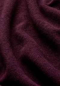 Tissu bordeaux avec une surface douce et texturée, présentant un léger côtelage et une drape douce. Le matériau semble chaud et agréable.