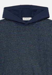 Felpa blu navy con materiale testurizzato e luccicante. Presenta una rifinitura in tessuto morbido attorno al colletto e un design a vestibilità standard.