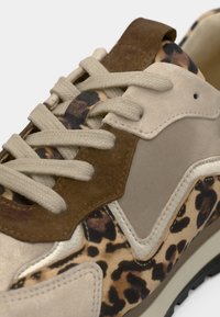 Αθλητικό παπούτσι με μοτίβο λεοπάρδαλης, διαθέτει μπεζ σουέντ και καφέ δερμάτινες λεπτομέρειες. Κορδόνια με υφή και ελαστική σόλα με λεπτομερή ραφές.